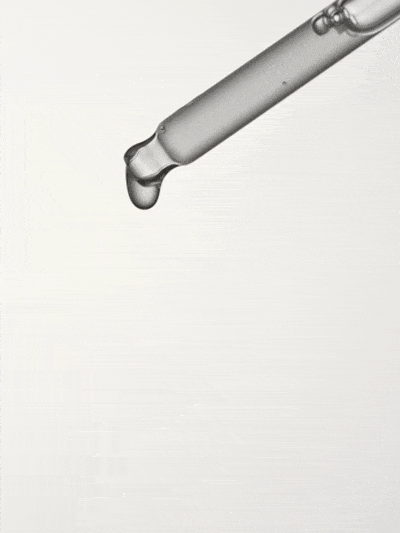 A clear glass dropper releasing a droplet of transparent liquid.
